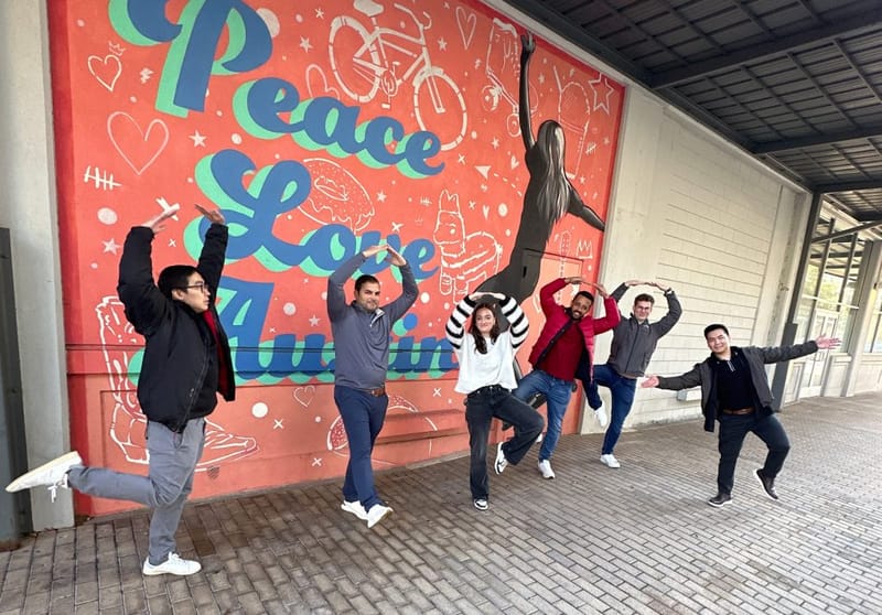 Six cityHUNT participants striking playful poses in front of a colorful Peace Love Austin mural