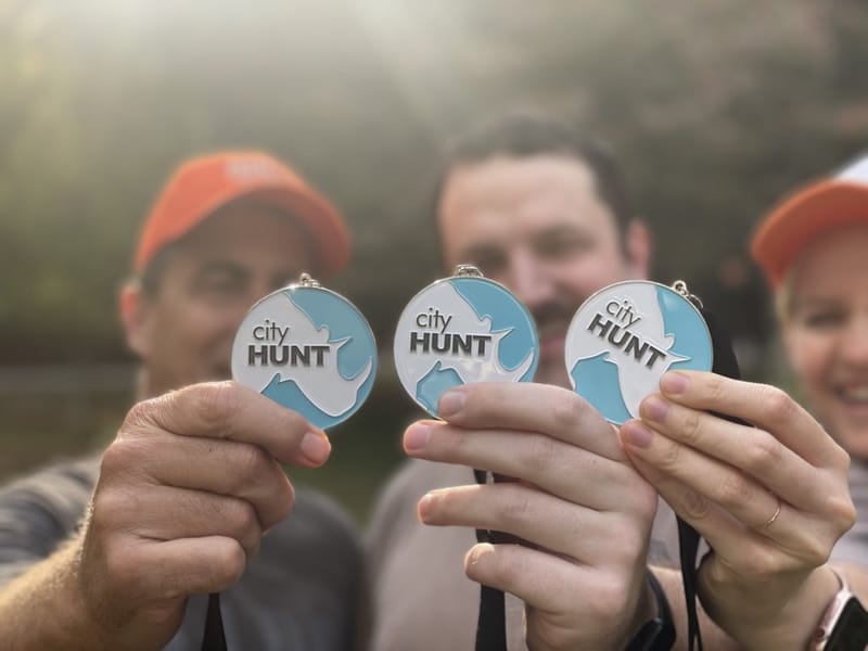 Three people holding up cityHUNT winner medals after a scavenger hunt event