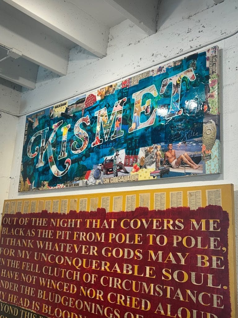 Two mixed-media artworks on a white wall: a colorful collage piece spelling KISMET in teal letters above a text painting featuring opening lines from the poem Invictus