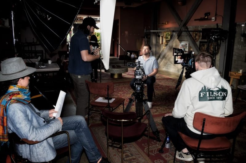 Ben Hoffman seated for a video interview in Nashville, with camera crew and softbox lighting surrounding him in a warmly lit venue