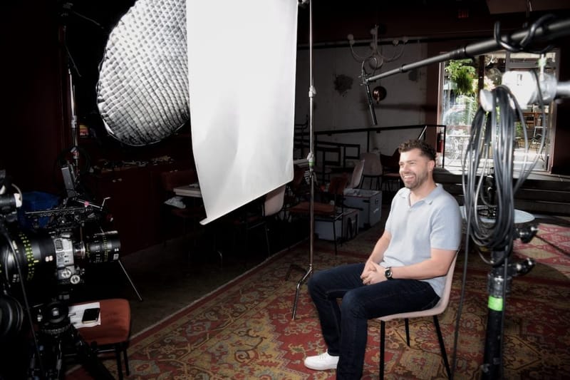 Ben Hoffman seated and smiling during a professional video interview shoot in Nashville, surrounded by studio lighting and a cinema camera