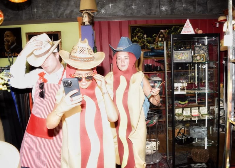 Three cityHUNT scavenger hunt participants in bacon and hot dog costumes with cowboy hats inside an eclectic Nashville shop